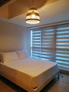 um quarto com uma grande cama branca e um lustre em Uptown Parksuites Apartments Tower 1 BGC by PH Staycation em Manila
