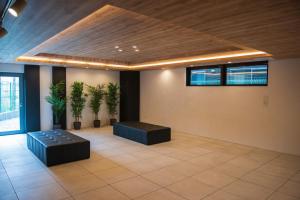 Pokój z 2 roślinami, kanapą i sufitem w obiekcie QUEENS PARK w Osace