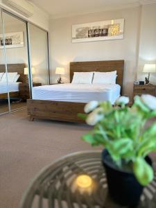 a bedroom with a bed and a table with a plant at Best location apartment in Olympic park in Sydney
