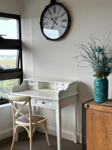 a desk with a chair and a clock on a wall at Best location apartment in Olympic park in Sydney +8 photos