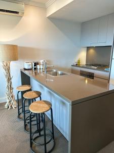 una cucina con due sgabelli e un bancone con lavandino di Best location apartment in Olympic park a Sydney