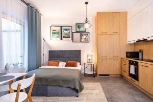 ein Schlafzimmer mit einem Bett und einem Tisch sowie eine Küche in der Unterkunft ApartamentySnu, Jagielloński Komfort, Centrum in Radom
