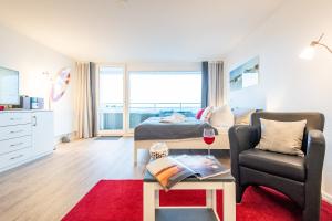 uma sala de estar com uma cama e uma cadeira e um copo de vinho em Hanseatenhaus Whg 79 Kramp em Westerland