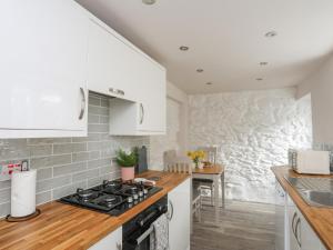 a kitchen with white cabinets and a stove top oven at 1 Bronrallt in Conwy