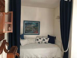 Un dormitorio con una cama blanca con cortinas azules. en L'appartement entre ciel et mer, en La Turballe