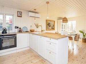 a kitchen with white cabinets and a wooden floor at Holiday home Kerteminde XII in Kerteminde