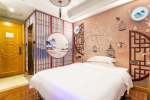 a bedroom with a white bed and a wall with flowers at Puzzle Hotel - Zhongshan 8th Road Chenjiaci Subway Station Branch in Guangzhou