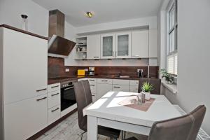 uma cozinha com armários brancos e uma mesa com cadeiras em Residenz von Flotow Wohnung 13 em Heiligendamm