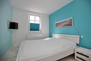 um quarto com uma cama branca e uma parede azul em Residenz von Flotow Wohnung 13 em Heiligendamm