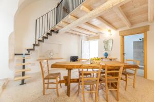 een eetkamer met een houten tafel en stoelen en een trap bij Casa Harem in Taurisano