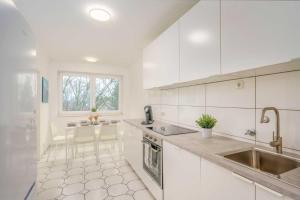 a kitchen with white cabinets and a sink and a table at Modern Apartment near Bottrop in Gladbeck
