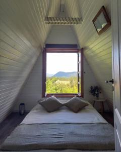 Bett in einem kleinen Zimmer mit Fenster in der Unterkunft Erdő Lelke Vendégház: mesebeli, erdőszéli faház panorámával in Nagymaros
