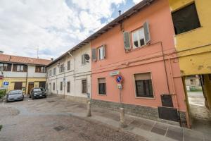a pink building with cars parked in a parking lot at My House&Apartments in Agrate Brianza