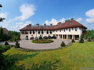 een groot gebouw met auto's geparkeerd op een binnenplaats bij Hotel & Restauracja Timberland in Orzesze