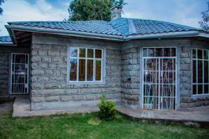 a small stone house with a large window at Lovely Spacious 3-Bed All EnSuite House in Nanyuki in Nanyuki
