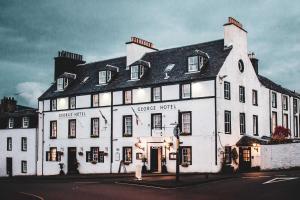 a large white building on the corner of a street at The George Hotel in Inveraray
