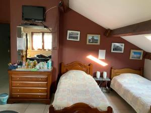 a bedroom with two beds and a dresser with a mirror at Le Castillon in Trivières