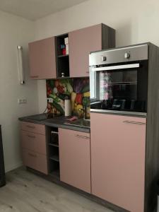 a kitchen with pink cabinets and a stove top oven at Ferienwohnung Sonne in Landstuhl