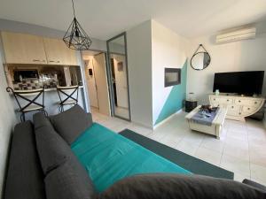 - un salon avec un canapé et une télévision dans l'établissement appartement T2 climatisé avec piscine secteur richelieu, au Cap d'Agde