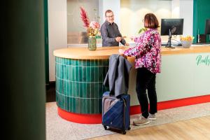 a woman standing in front of a counter with at ACHAT Hotel Stuttgart Airport Messe in Stuttgart