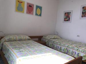 2 camas en una habitación con pinturas en la pared en L' Ulivo Villa Nunzia, en Isquia