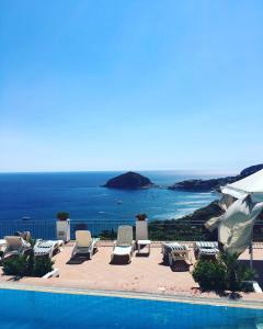 una piscina con sillas y vistas al océano en L' Ulivo Villa Nunzia, en Isquia