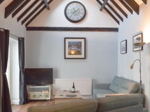 a living room with a couch and a clock on the wall at Stable Cottage in Penally