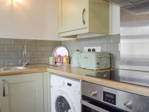 a kitchen with a washing machine and a washer at Stable Cottage in Penally