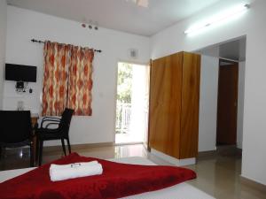 a bedroom with a red bed with a desk and a window at Drizzle Valley Cottage in Munnar +49 photos