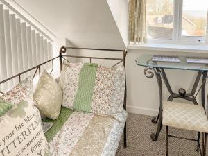 a bedroom with a bed and a table and a chair at Stable Cottage in Penally