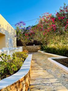 a garden with pink flowers and a stone walkway at Villa con piscina gigante in Sant Francesc de s'Estany