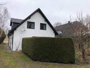 a white house with a hedge in front of it at Seestr 75 a Haus A links in Zingst