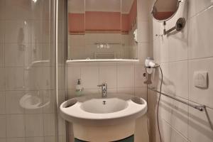 La salle de bains est pourvue d'un lavabo blanc et d'une douche. dans l'établissement Wohnpark Niendorf Wohnpark Niendorf Appartement 05, à Niendorf