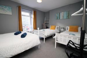 a bedroom with two beds and a chair at Cosy 2 Bed Flat 1 in Bridgend in Bridgend