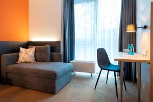 ein Wohnzimmer mit einem Sofa, einem Stuhl und einem Tisch in der Unterkunft ACHAT Hotel Stuttgart Airport Messe in Stuttgart