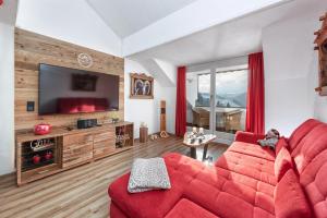 a living room with a red couch and a flat screen tv at Alpenliebe-mit Bergblick in Oberstaufen