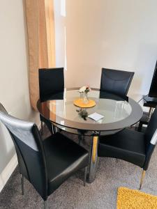 a dining room table with four chairs and a table with flowers on it at City Blessed Aptm 3 with Free Parking in North Shields