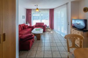 a living room with a red couch and a tv at Ferienhaus Seewind 11/1 in Werdum