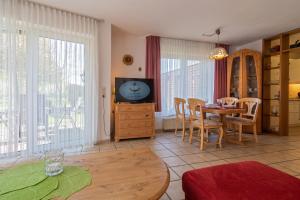 a living room with a television and a table and chairs at Ferienhaus Seewind 11/1 in Werdum