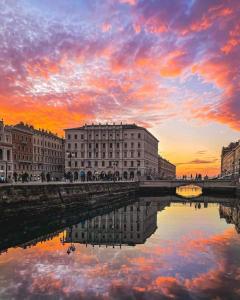 a sunset over a river with buildings and a bridge at Torretta International in Trieste