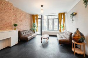 a living room with leather furniture and a brick wall at Two-Bedroom Apartments in the Heart of Antwerp in Antwerp