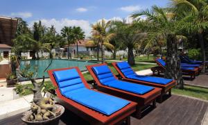 a group of blue lounge chairs next to a swimming pool at Puri Saron Hotel Baruna Beach Lovina in Lovina