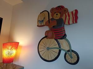 Un ours en peluche sur un vélo sur le mur dans l'établissement Au Coeur d'Acren, à Lessines