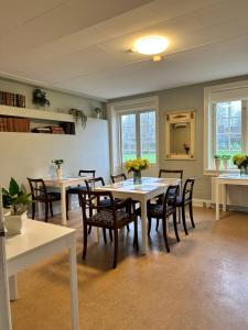 una sala da pranzo con tavoli, sedie e finestre di Forvalterboligen a Hadsund