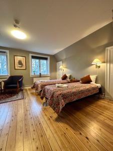 2 letti in una camera con pavimenti in legno e 2 finestre di Forvalterboligen a Hadsund