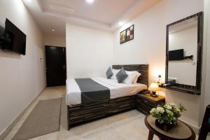 a bedroom with a large bed and a mirror at Umra Grace - Hotel in Haridwar By Perfect Stayz in Haridwār