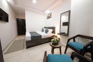 a bedroom with a bed and a mirror and a chair at Umra Grace - Hotel in Haridwar By Perfect Stayz in Haridwār