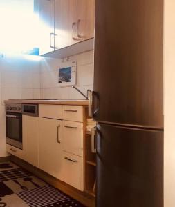 una cocina con nevera de acero inoxidable y armarios blancos en zentrale,vollausgestattete Ferienwohnung - 3 Zimmer, Petrovic, en Kapfenberg