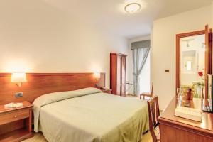 una camera con letto, scrivania e specchio di Hotel Flavio a Roma