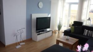 a living room with a couch and a tv at Ferienwohnung Deichblick in Dornumersiel